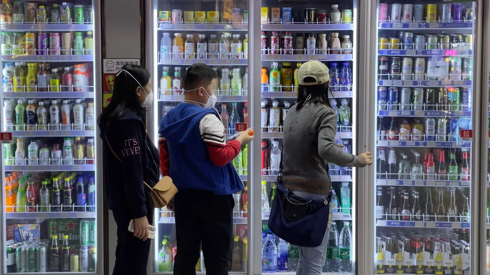 一些女性站在一台自动售货机前 正在看饮料。