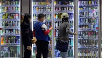 一些女性站在一台自动售货机前 正在看饮料。