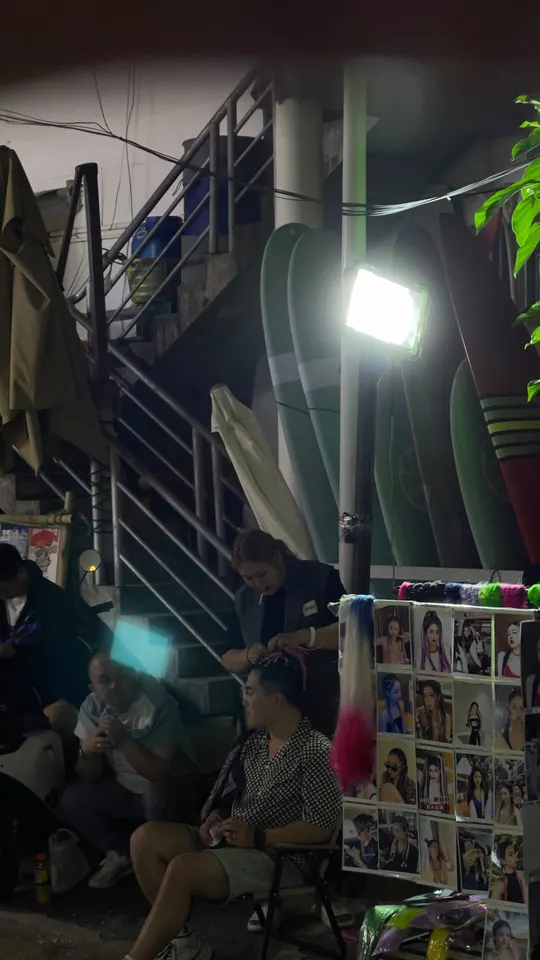 一个人坐在椅子上 下面有一些人的照片 在灯光下。