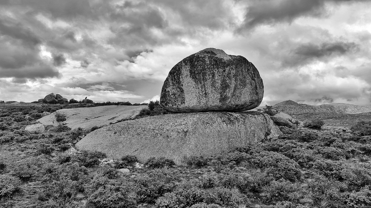 黑白风景画 描绘了一个巨大的岩石在田野中。