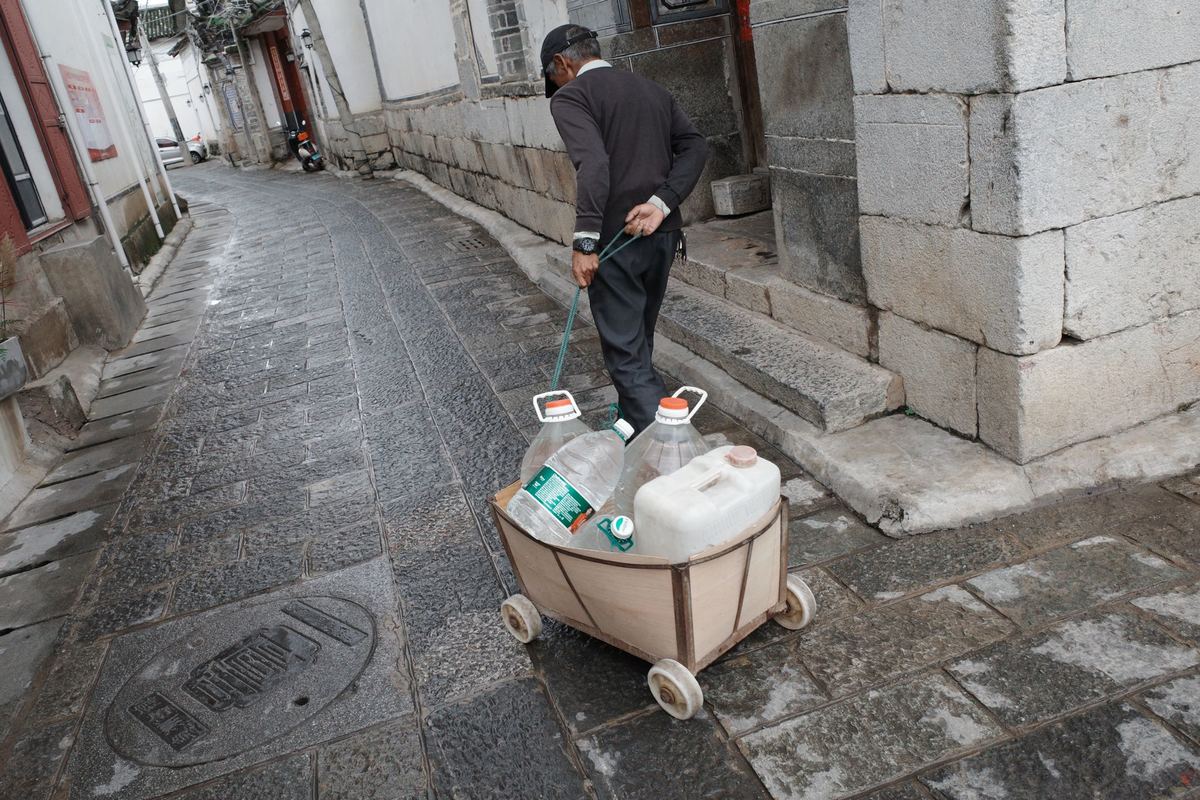 一个人推着装满干净水的推车穿过街道。