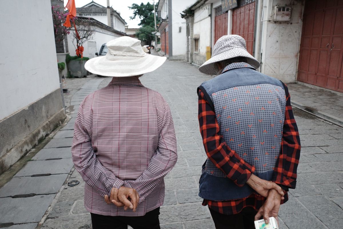 一对老年夫妇戴着帽子走下狭窄的街道