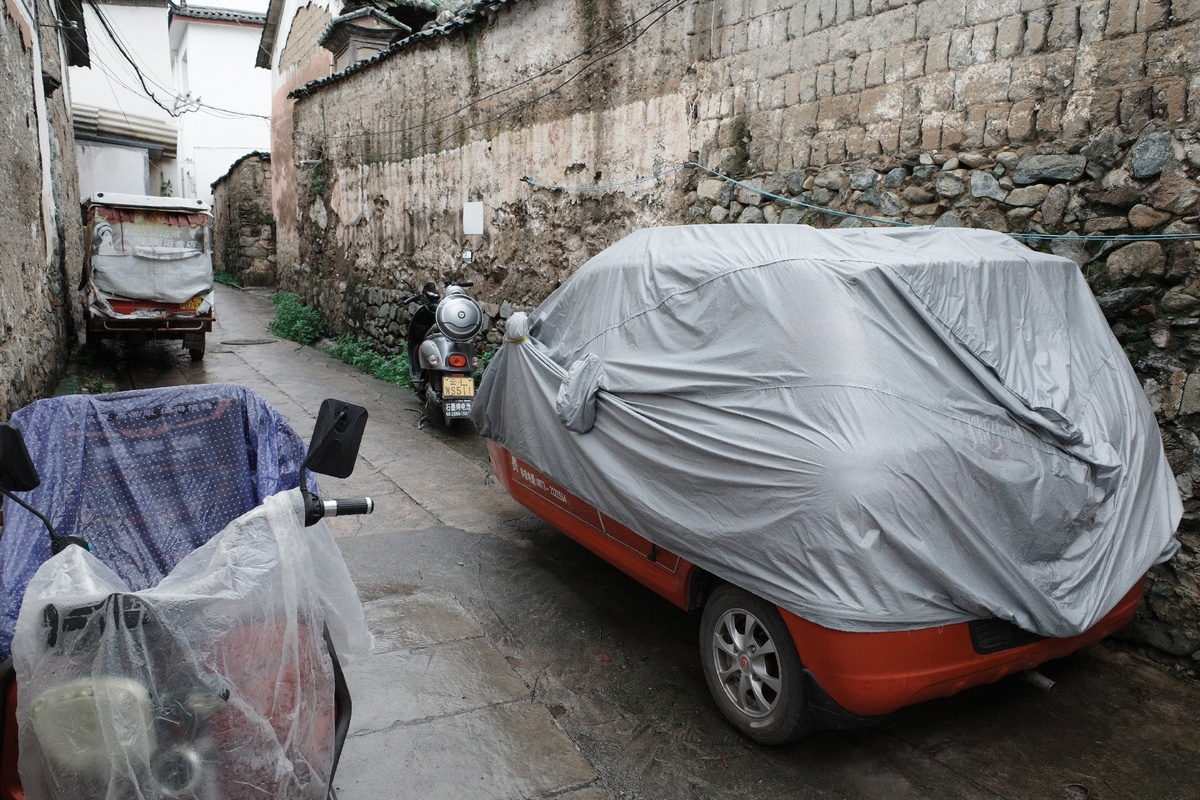 一辆塑料覆盖的小汽车停在一条狭窄的巷子里