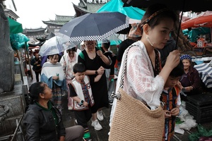 一位女士站在人群中 手持雨伞 在雨中。