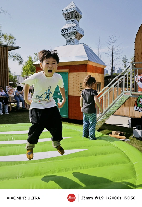 一个年轻男孩在蹦床上跳跃 其他孩子在背景中玩耍。