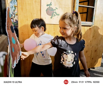 一个小男孩站在一个小女孩旁边拿着一个气球