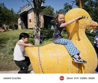 一个年轻男孩和一个小女孩在一个公园的游乐场上玩耍 一个巨大的黄色鸭子坐在游乐场上。