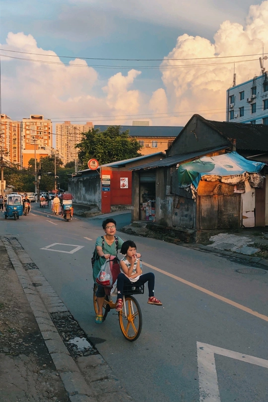 一男一女骑着自行车走在街上 自行车上有一个小男孩
