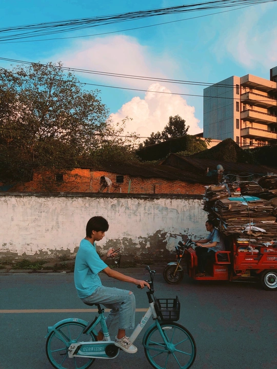 一个年轻人骑着一辆蓝色自行车沿街而行