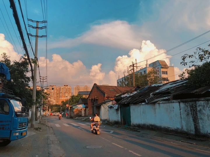 一条城市的街道 一辆蓝色卡车在路上行驶 人们骑着摩托车