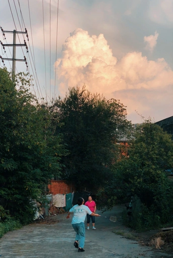 一个人和一个孩子在街上打棒球 而一个人带着风筝走在路上