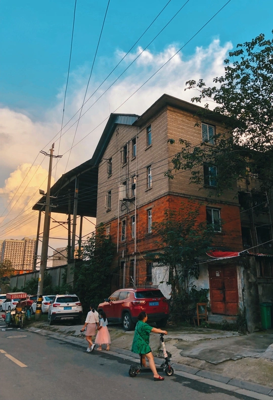一条有建筑物、汽车和几个骑自行车和踏板车的人的城市街道
