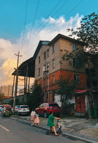 一条有建筑物、汽车和几个骑自行车和踏板车的人的城市街道