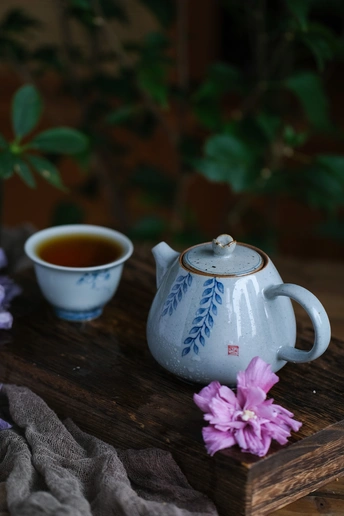 放在桌子木托盘上的茶壶和一杯茶