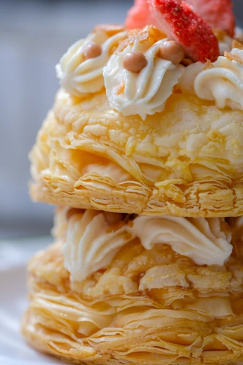 一堆薄煎饼 上面放着生奶油和一颗草莓 放在一个白色盘子里