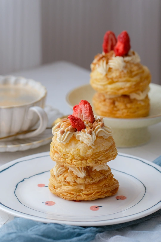 一堆白色盘子里放着奶油和草莓的糕点