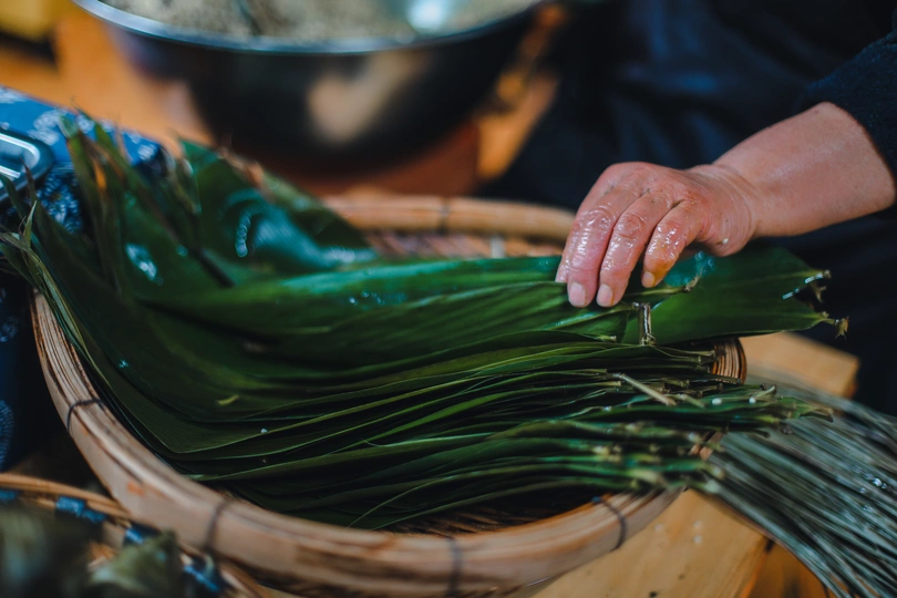 一个人拿着一个装满绿色海藻的篮子 旁边放着一个碗和食物。