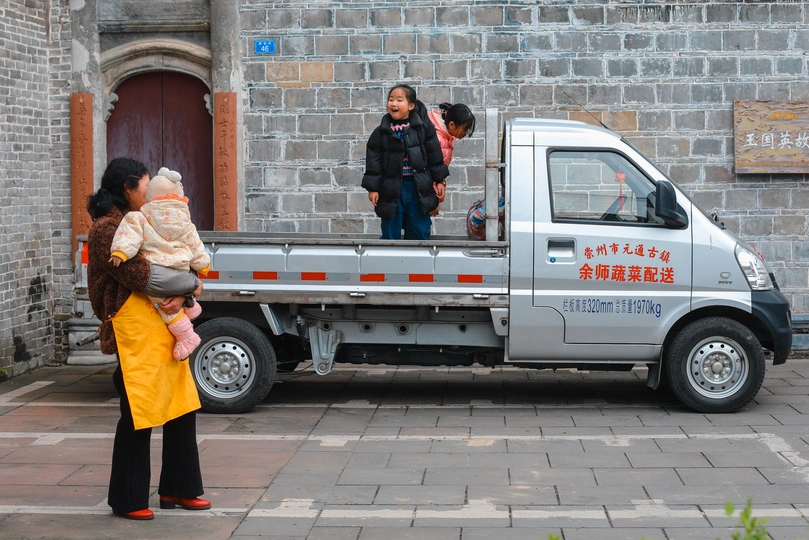 一位妇女抱着一个小孩子站在一辆卡车旁边