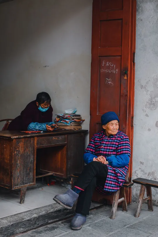 一位老妇人在街上坐在一个小桌子上