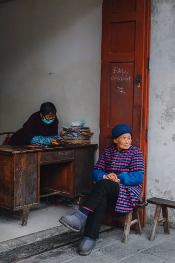 一位老妇人在街上坐在一个小桌子上