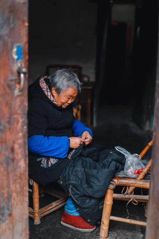 一位老人坐在一位年长的男子旁边的一把木椅上。