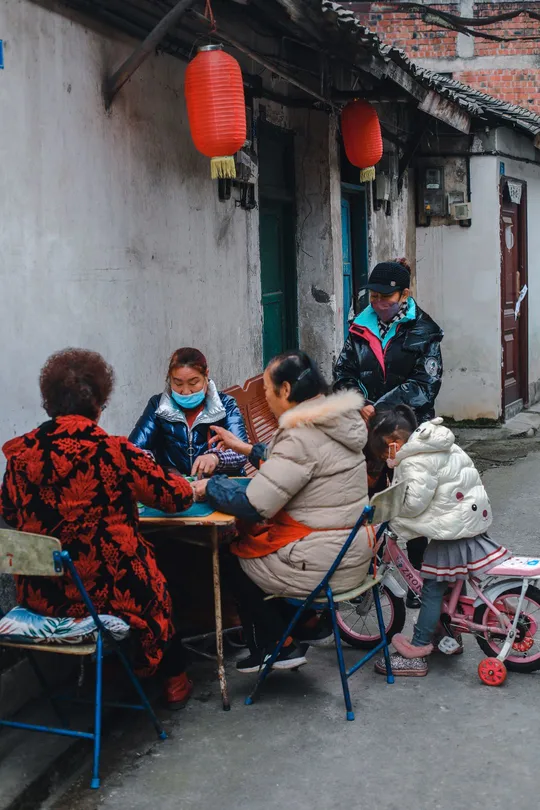 人们戴着口罩坐在一条小巷的桌子旁