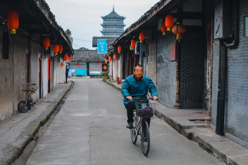 一个骑自行车的人在空荡荡的街道上行驶 街道两旁是建筑物。