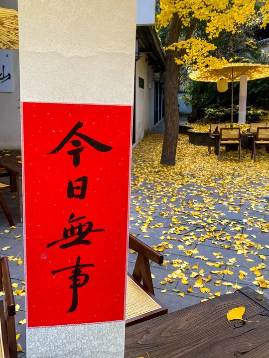 红色和白色的标志 一张桌子和椅子 还有黄色的树。