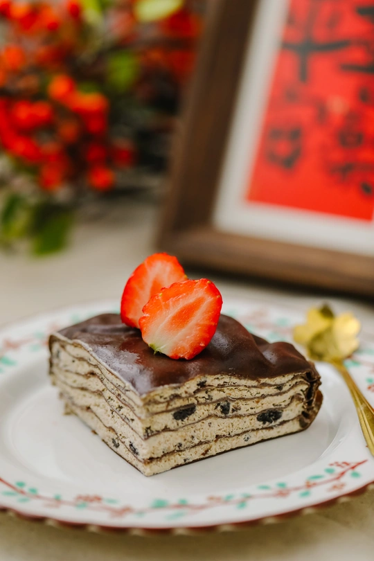 巧克力覆盖的一块小蛋糕和草莓放在白盘子上