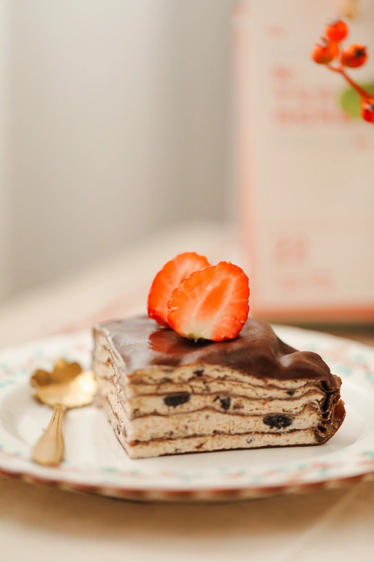 巧克力覆盖的一块小蛋糕和草莓放在一个白盘子上