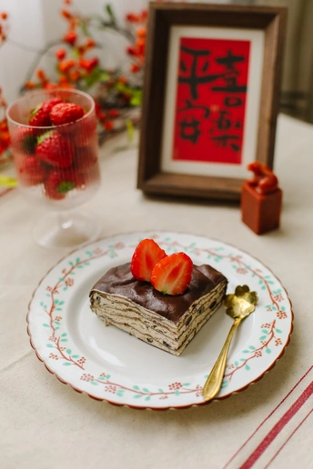 一片沙漠上有草莓的白色盘子 配有玻璃和勺子。