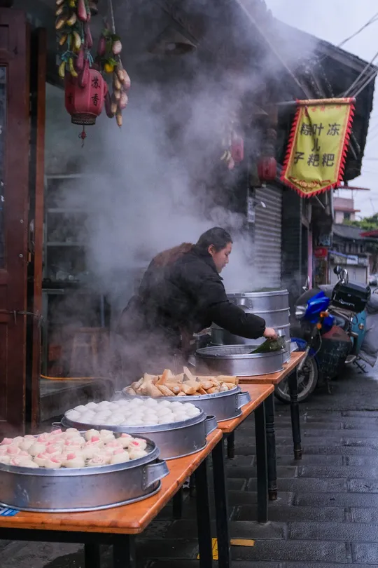 一个男人在街边的桌子上有烧烤架在烧烤食物。