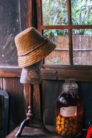 一顶旧帽子坐在木椅上 旁边有一个玻璃罐和瓶子。