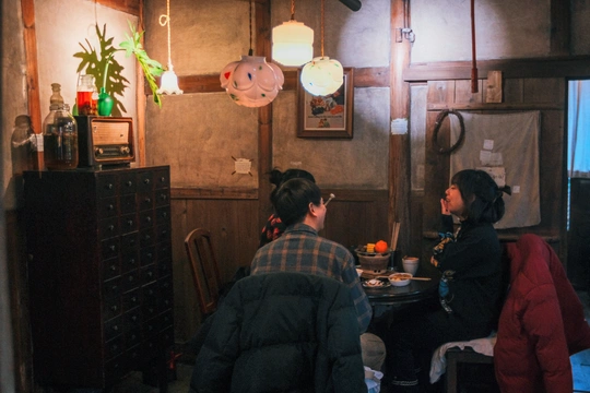 一个男子和一个女子坐在带有厨房的房间里的一张桌子旁