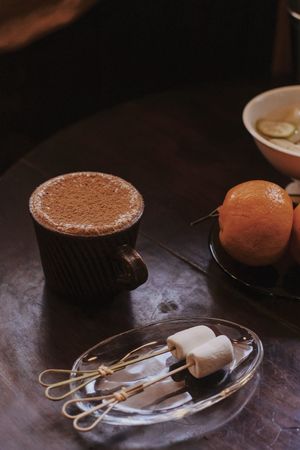 一盘食物放在一张桌子旁边 旁边有一杯巧克力和一个橙子碗。