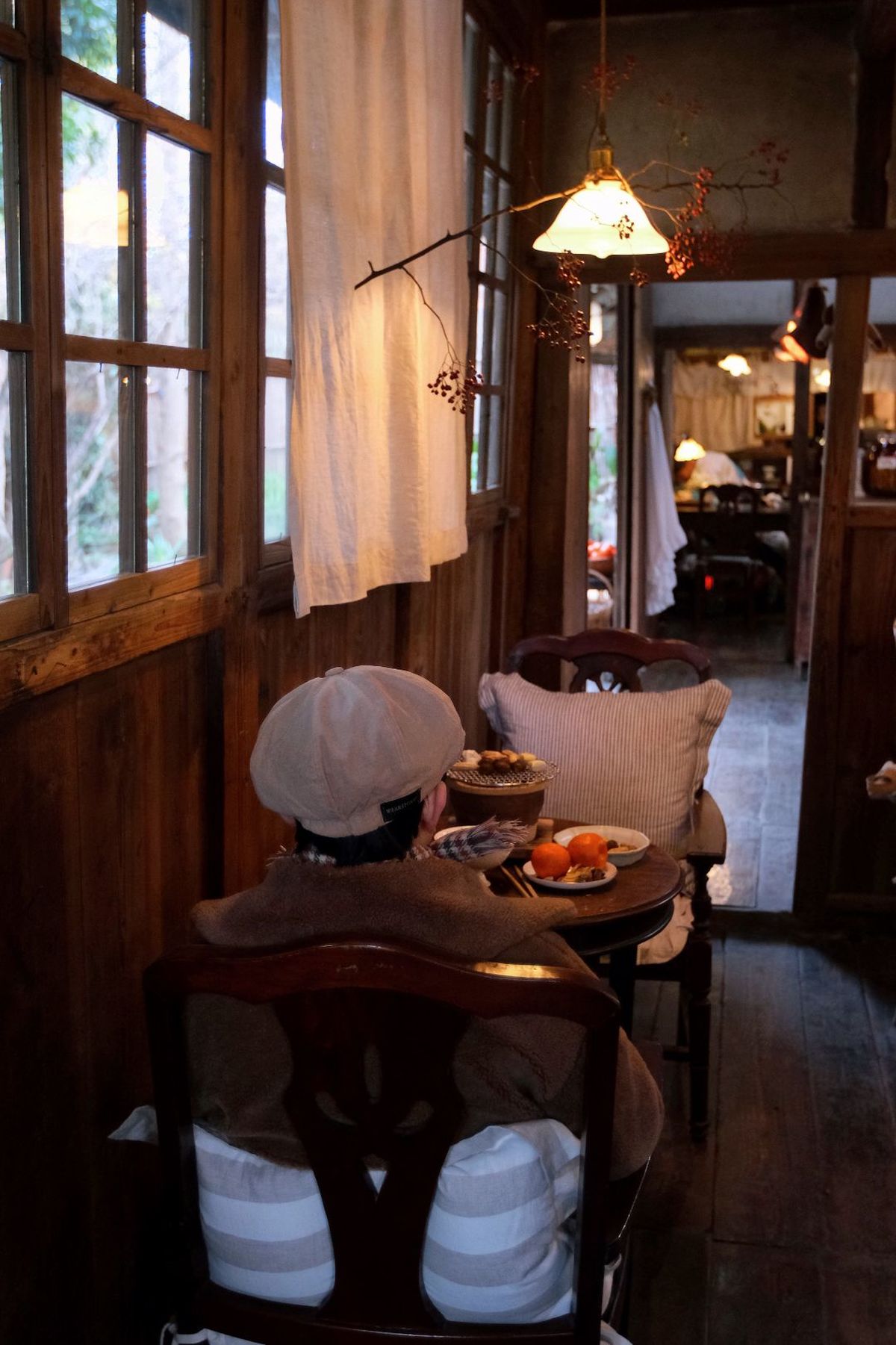 在车厢内 透过餐厅、厨房和客厅的门 看到一张桌子和椅子 桌子上放着一顶帽子 盘子里装着食物。