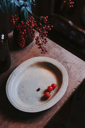 一个空白的瓷碗放在木桌上 旁边有一棵小植物。