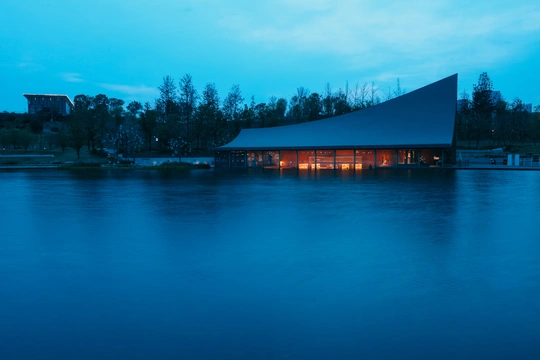 夕阳下 一栋建筑在水边亮了起来。