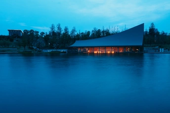夕阳下 一栋建筑在水边亮了起来。
