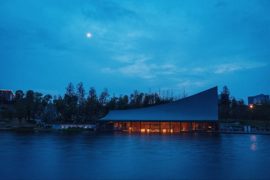 夜晚中 一栋大建筑被满月映照在蓝色的天空中。