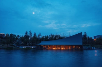 夜晚中 一栋大建筑被满月映照在蓝色的天空中。