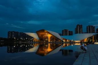 夜晚被月亮照亮的城市 前面有建筑物和湖泊。