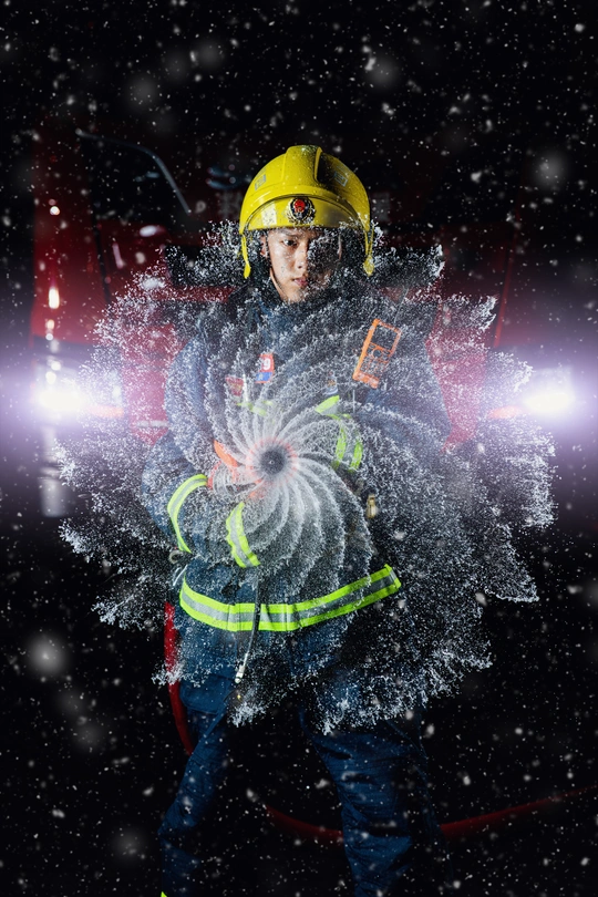 一个戴头盔的年轻消防员站在黑暗中