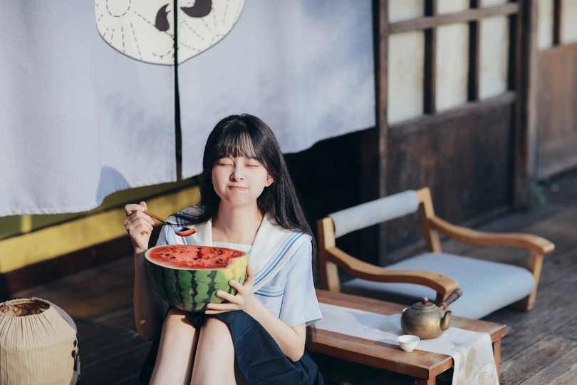 一个年轻的女人拿着一碗西瓜坐在地板上