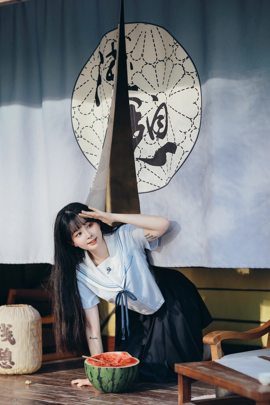 一位留着长发的年轻女子拿着一碗水果在舞台前摆姿势