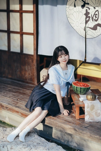 一个年轻的女人坐在木凳上 旁边是桌子上的一个碗