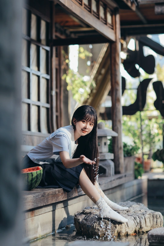 坐在喷泉上喝水的年轻女子