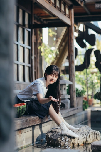 坐在喷泉上喝水的年轻女子