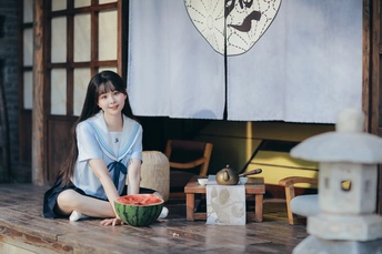 一个年轻的女人坐在地板上一碗西瓜前