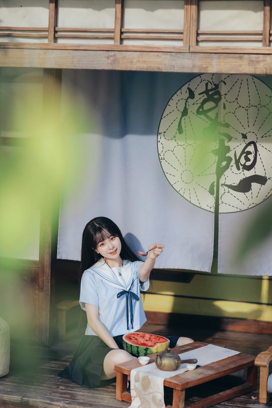 一位年轻女子坐在桌子前的长椅上 地板上放着一碗水果